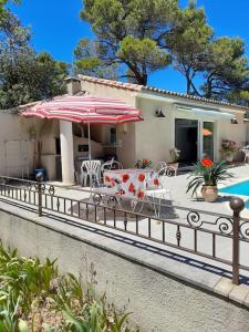 una casa con patio con tavolo e ombrellone di Villa le Bosquet en Luberon. a Ménerbes