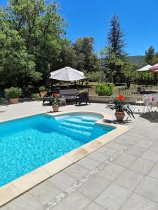 una piscina con tavolo e ombrellone di Villa le Bosquet en Luberon. a Ménerbes