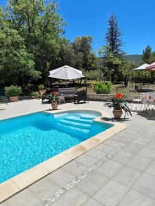une piscine avec une table et un parasol dans l'établissement Villa le Bosquet en Luberon., à Ménerbes