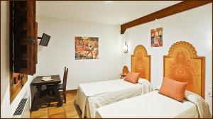 um quarto de hotel com duas camas e uma secretária em Posada del Tio Juanón em Navalcarnero