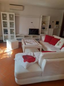 una sala de estar con muebles blancos y almohadas rojas. en LA CASA DI GIADA, en Impruneta