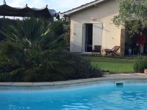 a blue swimming pool in front of a house at Tranquillité et confort aux portes de Bordeaux in Cénac