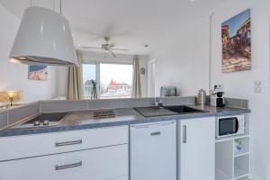 a kitchen with white cabinets and a sink and a window at La Rose des Sables Arcachon in Arcachon