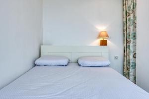 a small bedroom with a white bed and a lamp at La Rose des Sables Arcachon in Arcachon