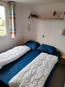 a bedroom with two beds and a window at BJ Chalets - Robbengat 85 - Gezellige, kindvriendelijke chalet op vakantiepark Lauwersoog! Vroege incheck! in Lauwersoog