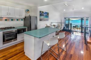 a kitchen with white cabinets and a island with a counter top at The Panorama 3, Hamilton Island 2 Bedroom 2 Bathroom Ocean View Modern Apartment in Hamilton Island