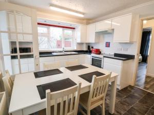 a white kitchen with a table and chairs in it at 17 Third Avenue in Prestatyn