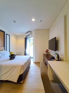 a hotel room with a bed and a flat screen tv at Zia Sanno Menteng Residences- Jakarta in Jakarta