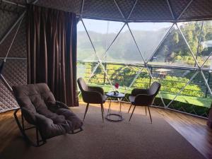a room with two chairs and a table in front of a large window at Glamz Hills in Cameron Highlands