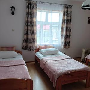 two beds in a room with a window at Klimatyczny Domek in Sławęcin