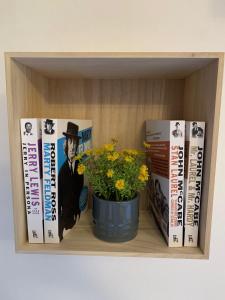 een boekenplank met boeken en een pot bloemen bij Casa di Arianna in centro storico a Vimercate in Vimercate