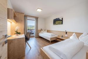 een hotelkamer met 2 bedden, een bureau en een kamer bij Haus Pötzes in Castelrotto