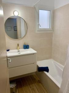 a bathroom with a sink and a tub and a mirror at villa bleu marine chic calme et jardin in Andrézieux-Bouthéon