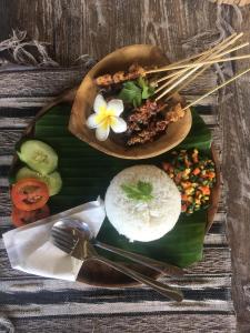 a plate of food with rice and a flower on it at Makawi Tuwa Cliff - Luxury Cliff Stay with Private Beach, Infinity Pools and Ocean View in Seraya +28 photos