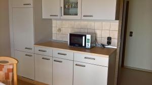 uma cozinha com armários brancos e um micro-ondas no balcão em Ferienwohnung-Anja em Fladungen