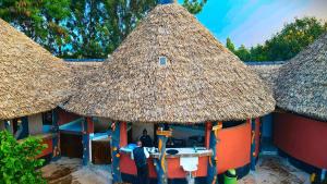 Jambo Afrika Resort في Emali: كوخ صغير بسقف من القش فيه رجل