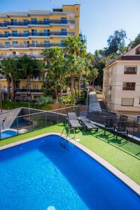 a swimming pool with chairs and a building at Hotel Acacias Suites & Spa in Lloret de Mar