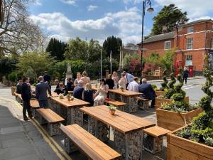 a group of people sitting at tables in a garden at The Bull Inn in Woodbridge