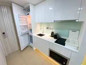 a white kitchen with a sink and a refrigerator at Sands Condo Pattaya 82 by ThaiminatorPattaya in Pattaya South