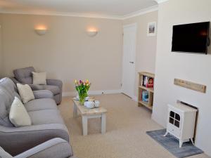 a living room with a couch and a tv at Silvershell View in Port Isaac