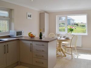 a kitchen and dining room with a table and a microwave at Silvershell View in Port Isaac