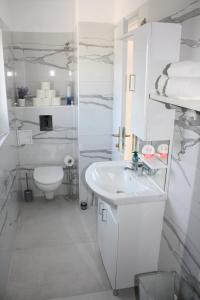 Baño blanco con lavabo y aseo en Apartments Adria, en Tribunj