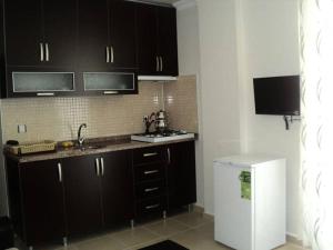 a kitchen with black cabinets and a white refrigerator at ELSİRA APART in Side