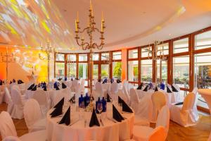 un salón de banquetes con mesas y sillas blancas y una lámpara de araña en Residenz Seehotel Berlin Brandenburg, en Motzen