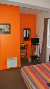 a bedroom with orange walls and a bed and a desk at Le Vieux Carré in Rouen