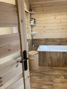 uma casa de banho com uma banheira ao lado de uma parede de madeira em Chata Peťo em Bžany