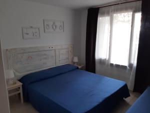 Un dormitorio con una cama azul y una ventana en La Casa di Adi, en Santa Caterina di Nardò