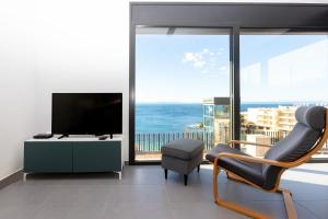 ein Wohnzimmer mit einem TV und einem Stuhl in der Unterkunft RNET - Casa 3 - Vista Mar Almadrava Roses in Roses