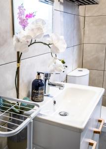 uma casa de banho com lavatório e flores brancas em Spacious Liverpool Central Apartment em Liverpool
