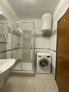 y baño con ducha y lavadora. en Etruria Residence, en San Vincenzo