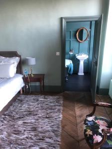 a bedroom with a bed and a sink and a mirror at Rouge Maison in Bois-Normand-près-Lyre