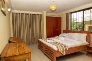 a bedroom with a bed and a table and a window at Runako Lodge in Arusha