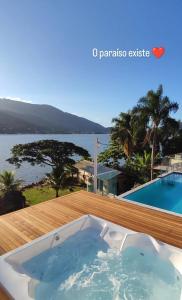 a hot tub on a deck with a view of the water at Paraíso da Enseada de Brito in Palhoça