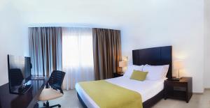 バランカベルメハにあるHotel Millenium Barrancabermejaのベッド、デスク、テレビが備わるホテルルームです。