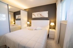 a bedroom with a large white bed and a mirror at Meritähti Apartments by Hiekka Booking in Kalajoki