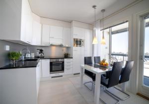 uma cozinha com armários brancos e uma mesa com cadeiras em Meritähti Apartments by Hiekka Booking em Kalajoki