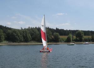 a small red and white sail boat on a lake at Ferienwohnung Wölfel in Schwarzenbach an der Saale