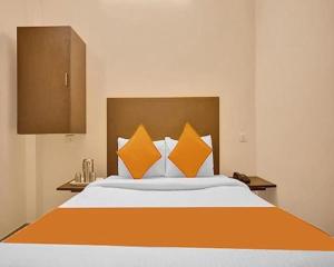 a bedroom with a large bed with orange pillows at FabExpress Joel Inn in Chennai