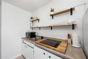 eine kleine Küche mit einer Spüle und einer Mikrowelle in der Unterkunft Cottage Bungalow Near Beach! 1 Bed with Pool & BBQ in Fort Myers