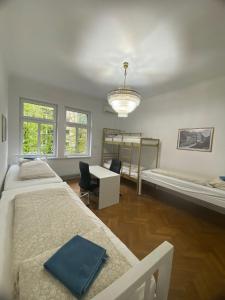 a bedroom with two beds and a desk and a chandelier at Rooms Miklošičeva in Ljubljana