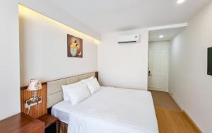 a small bedroom with a white bed and a desk at Xavia Hotel Quy Nhơn in Quy Nhon