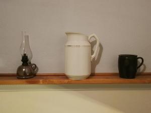 un jarrón blanco sentado en un estante con dos tazas en Ferien in der alten Scheune en Kurort Altenberg