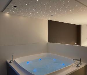 uma banheira com luzes azuis num quarto em Gite Spa L'Atelier Emile - Spa Privatif - 5 min COLMAR em Sainte-Croix-en-Plaine
