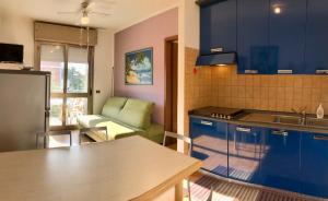 a kitchen with blue cabinets and a table and a couch at Condominio Aquila in Bibione