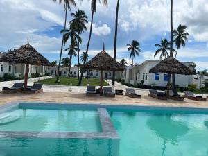 un complexe avec une piscine et des palmiers dans l'établissement Kiwengwa Minazi Resort, à Kiwengwa