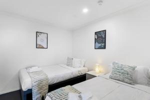 a white room with two beds and a couch at Superb 2BR Aprt in Central City - Wifi - Netflix in Auckland